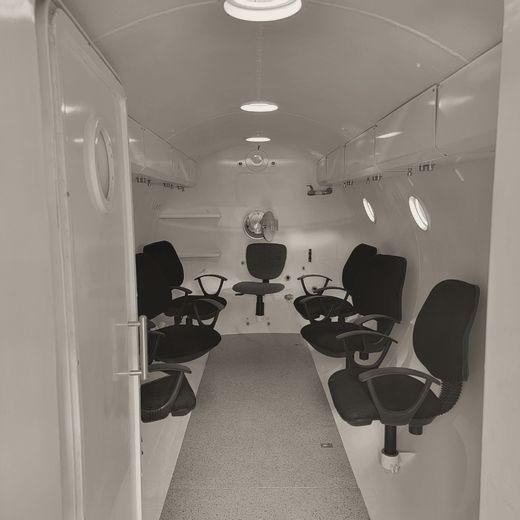 Interior of a multiplace chamber lined with seats and viewports